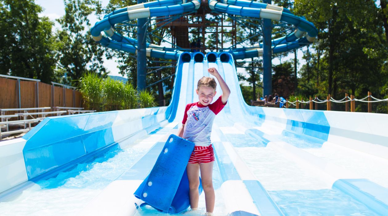 Kid celebrates after racing down a water slide