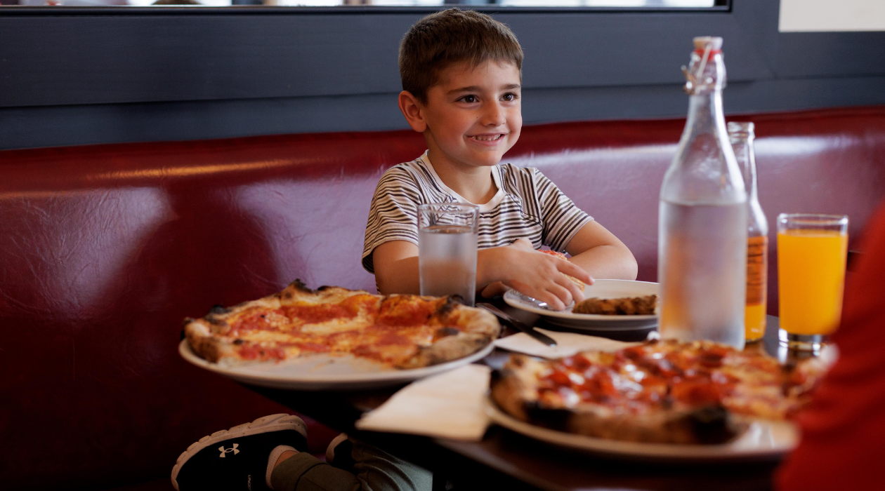 Pizzeria Posto kid sitting at table in front of pizza