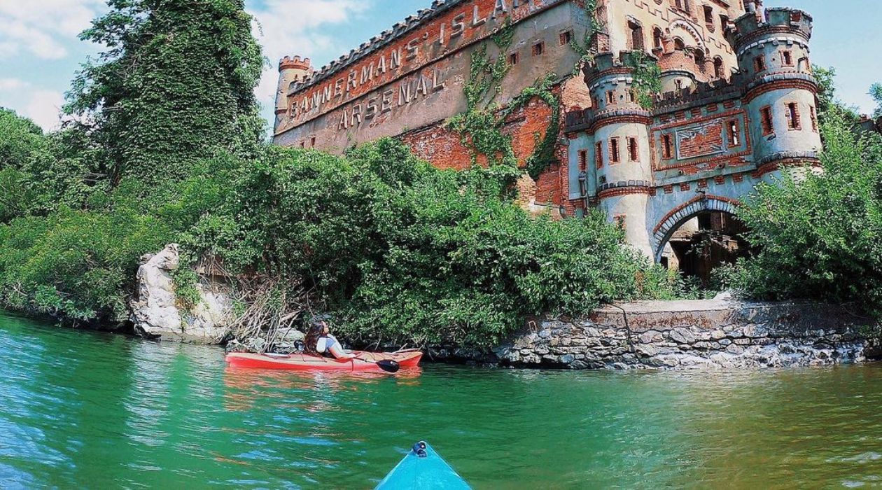 Two kayaks approach the banks of an island with Bannerman Castle 