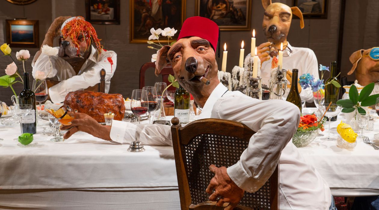 Sculpture of dogs dressed like humans at a dinner table