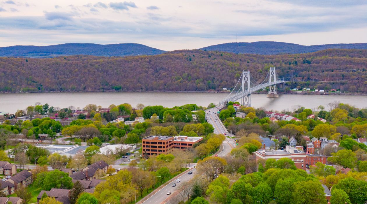Aerial view of Poughkeepsie, many Victorian buildings and brick buildings with bridge crossing the Hudson River in back spring