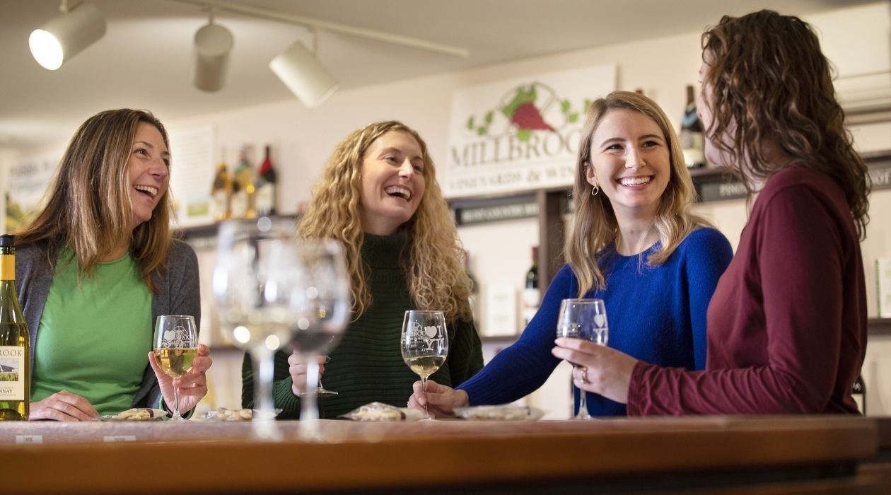 Four women sipping white wine inside a tasting room