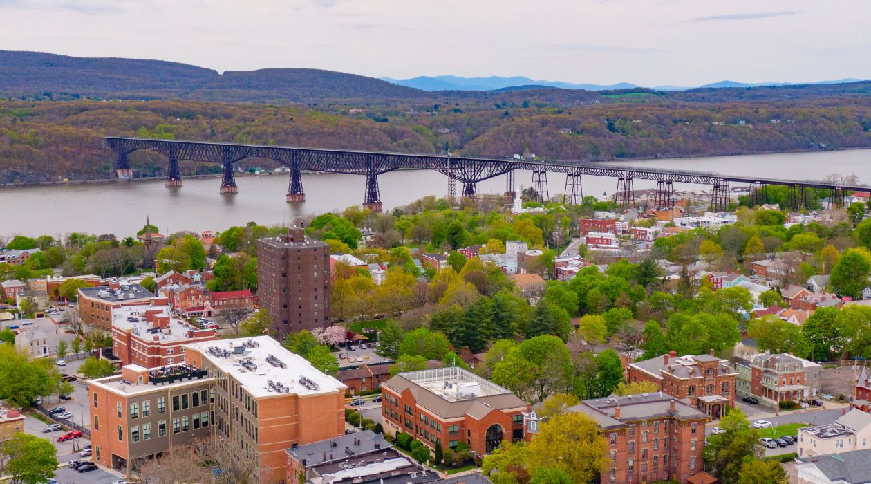 Aerial view of Poughkeepsie, many Victorian buildings and brick buildings with bridge crossing the Hudson River in back